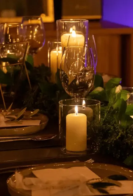 Velas e ramos verdes a decorar uma mesa de evento